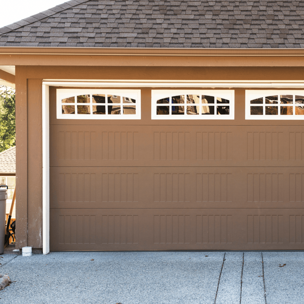 Beautiful brown carriage-style garage door with arched windows on residential home