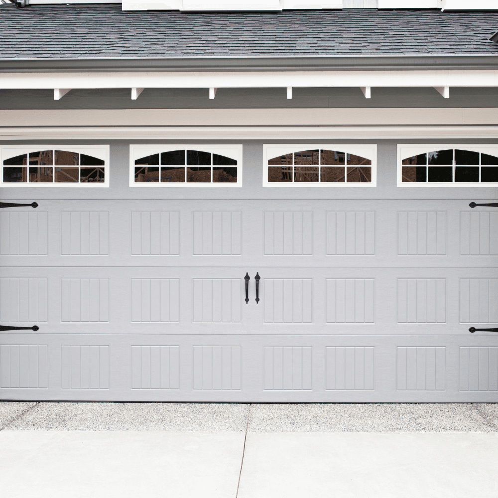 Gray carriage-style garage door with decorative hardware and arched windows